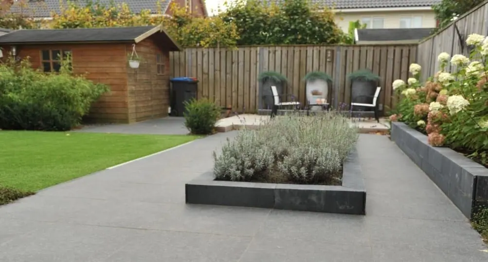 Tuin met gazon, tegelpad en een verhoogde plantenbak met lavendel