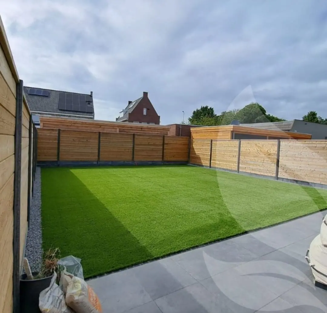 Tuin met gazon, tegelterras en een nieuwe houten schutting