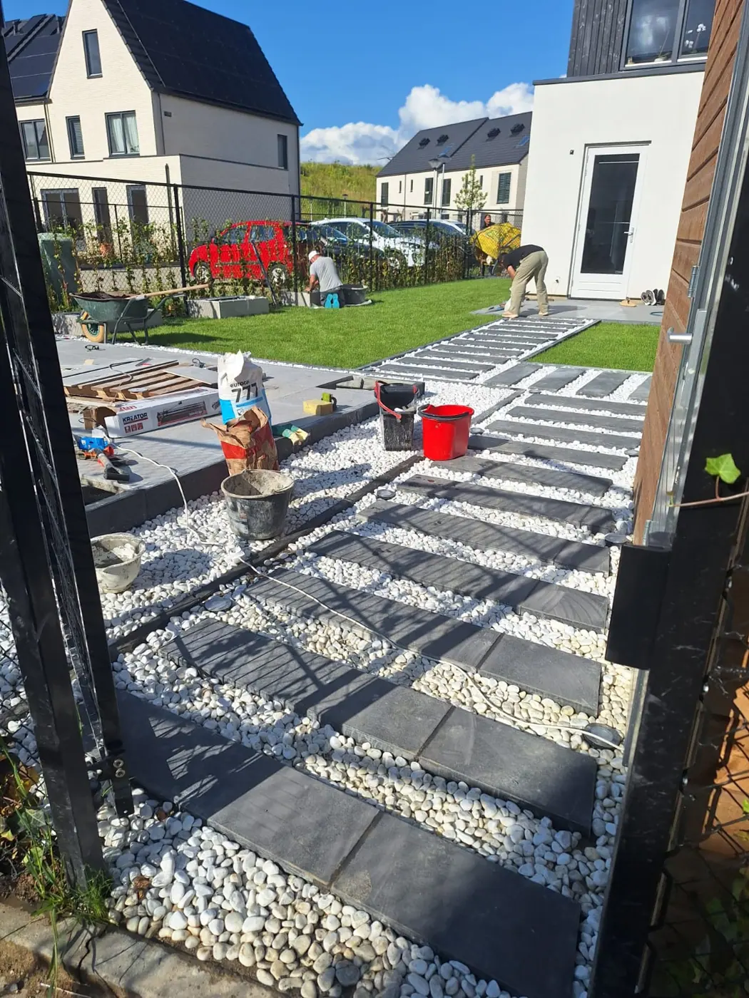 Tuin in aanleg: tegels worden gelegd tussen stroken grind