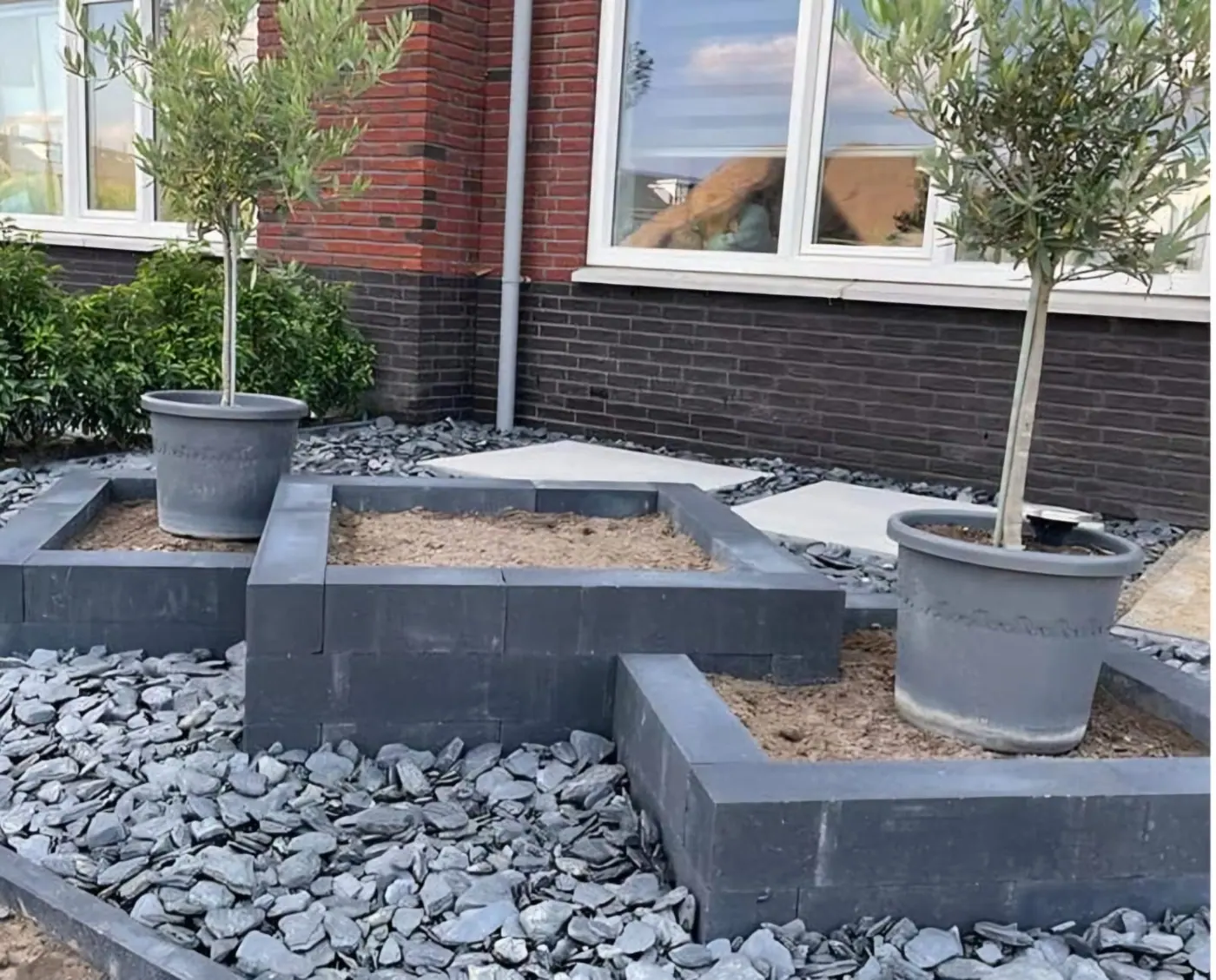 Verhoogde plantenbakken met leisteensplit en olijfboompjes in pot