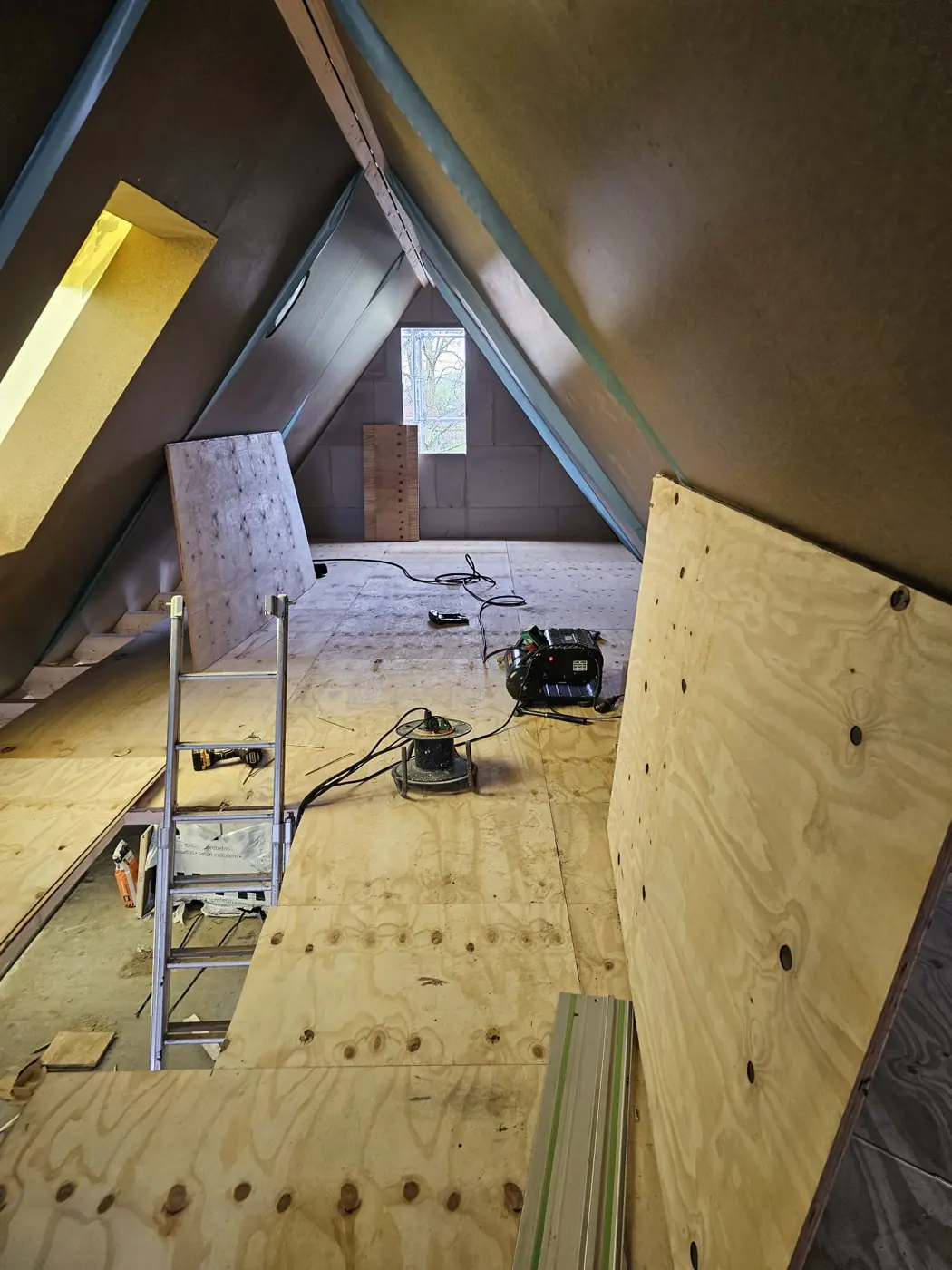 Zolder in opbouw met een vloer van plaatmateriaal en een dakraam
